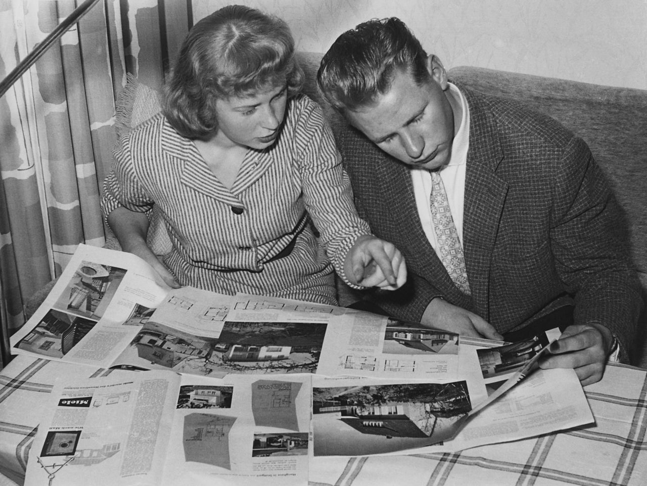 Historisches Bild junges Paar schaut Prospekte an