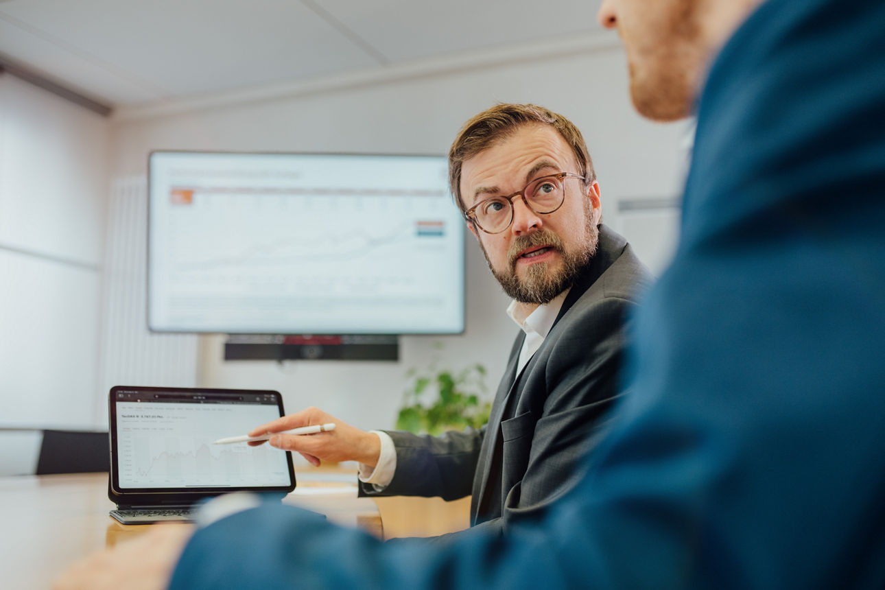Ein Mitarbeiter zeigt einem anderen Mitarbeiter eine Info auf dem Laptop