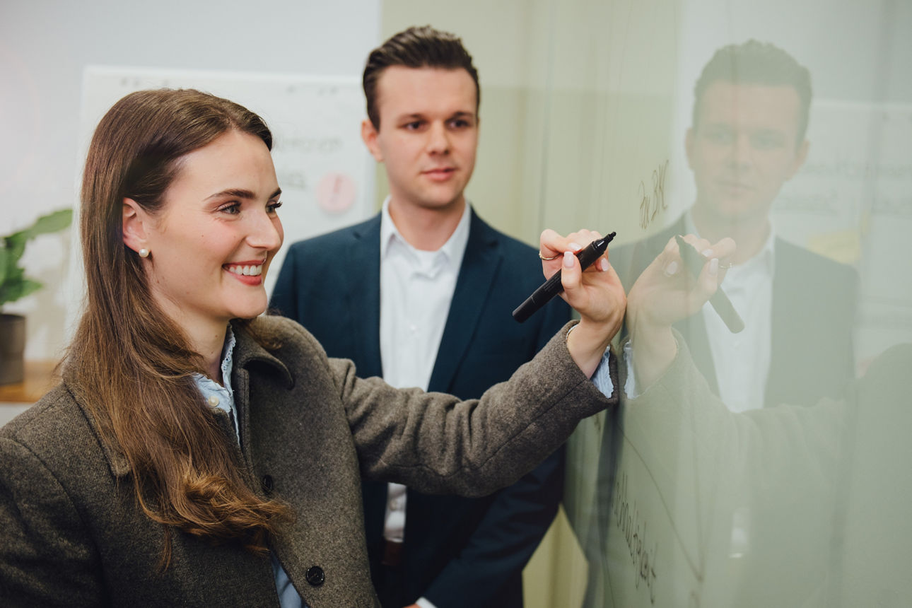 Eine Mitarbeiterin schreibt etwas an ein Whiteboard