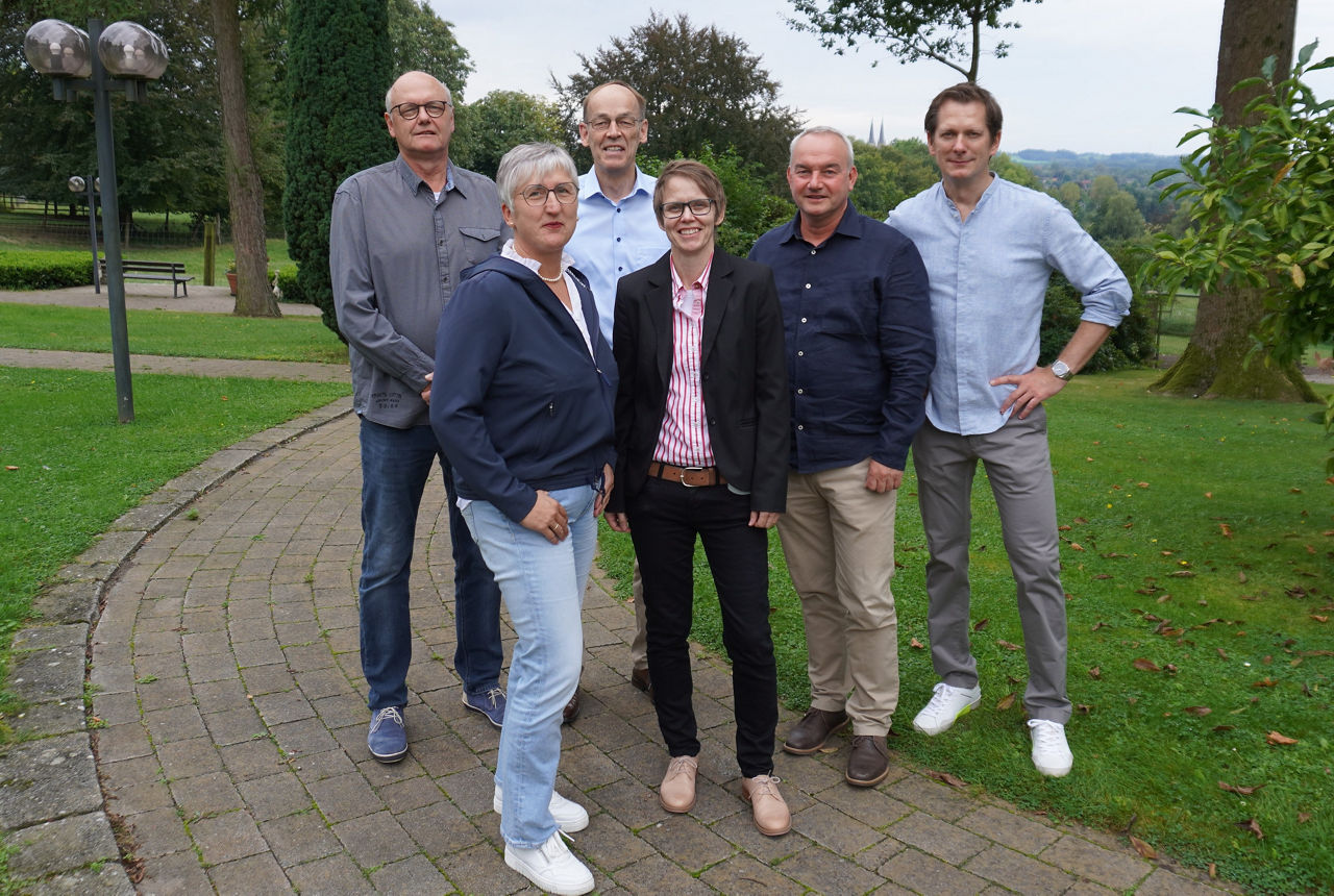 Fünf Personen stehen auf einem Steinweg in einem Park