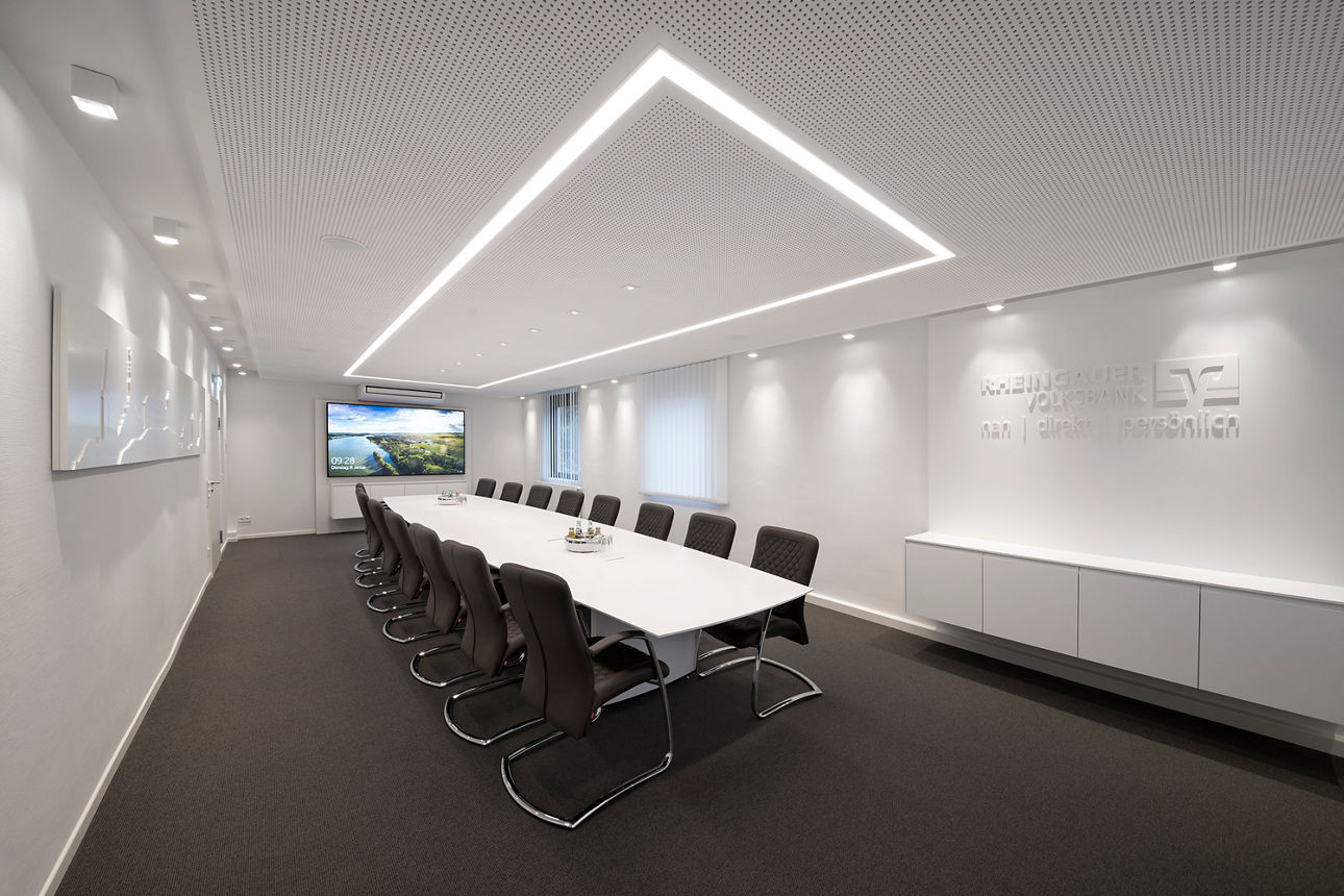 Blick in ein Sitzungszimmer mit Tisch, Stühlen und einem großen Bildschirm