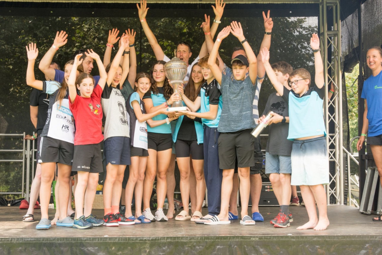 Eine Gruppe Kinder steht zusammen und hält einen Pokal in die Höhe