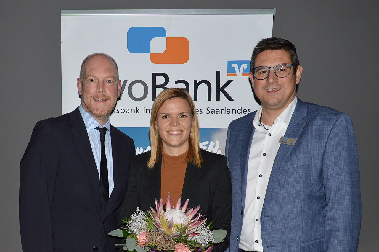 Eine Gruppe aus zwei Männer und einer Frau, die einen Blumenstrauß hält