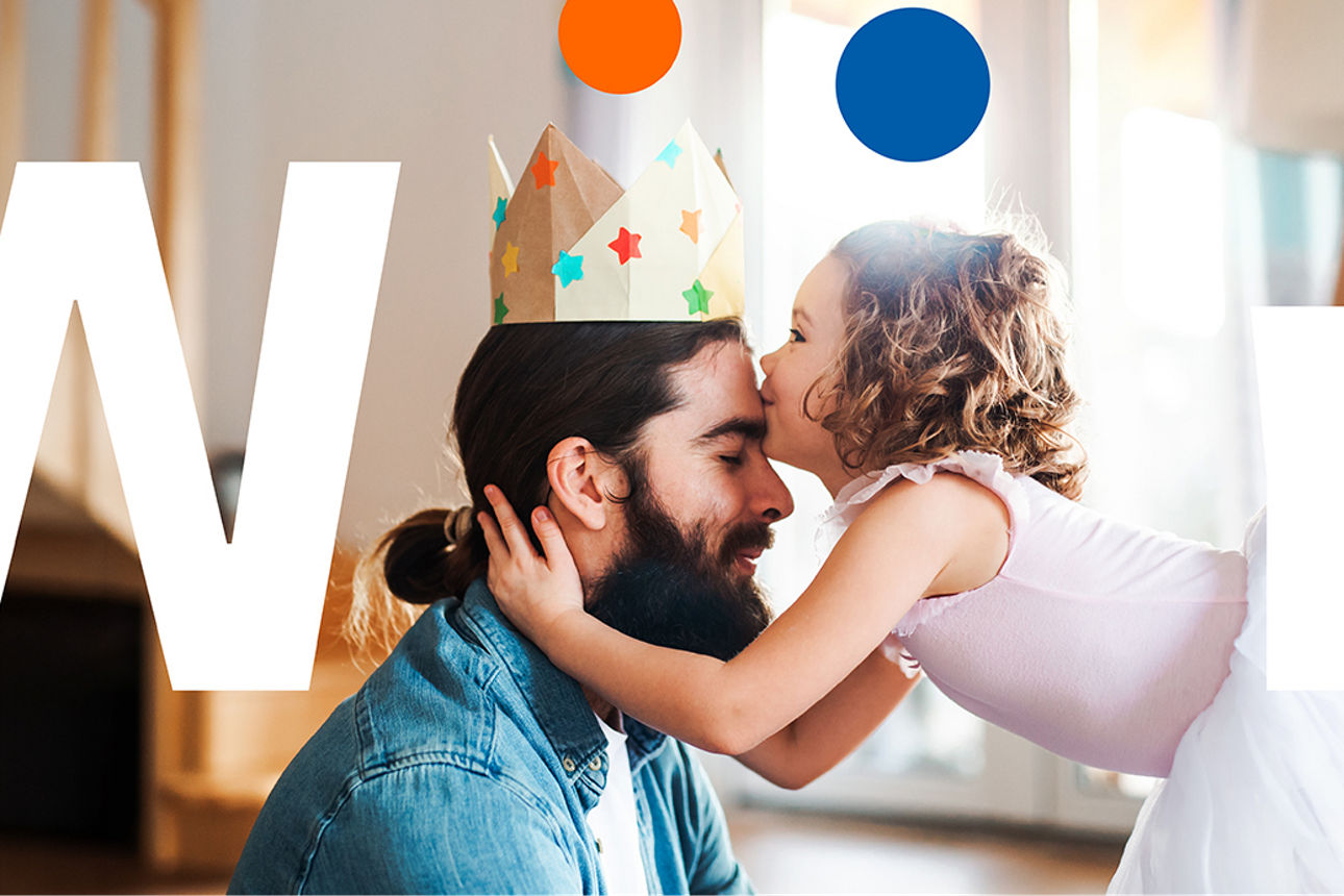 Vater mit einer Papierkrone bekommt eine Umarmung seiner kleinen Tochter