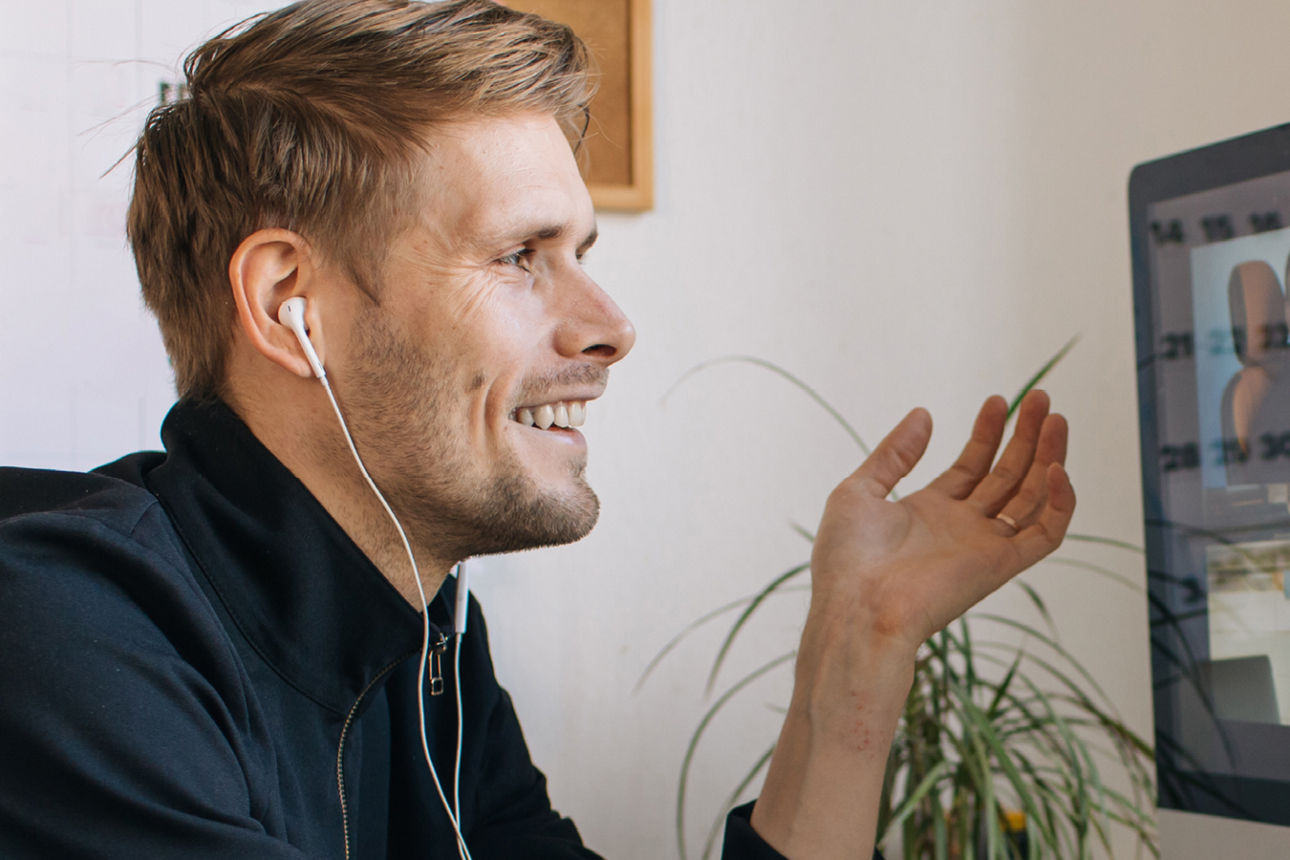 eine Person sitzt am Schreibtisch und führt ein Videomeeting 
