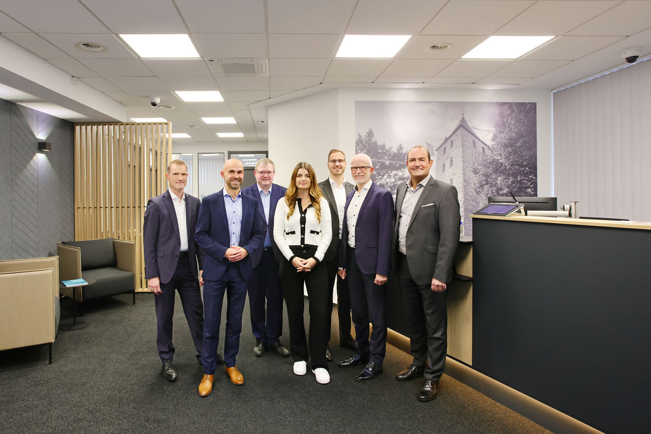 Mitarbeiter, Vorstandsmitglied und Regionalleiter stehen im modernisierten Kundenbereich der Filiale Elsen