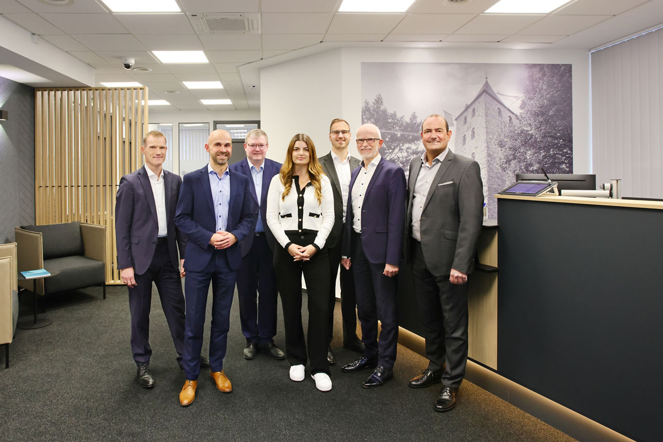 Mitarbeiter, Vorstandsmitglied und Regionalleiter stehen im modernisierten Kundenbereich der Filiale Elsen