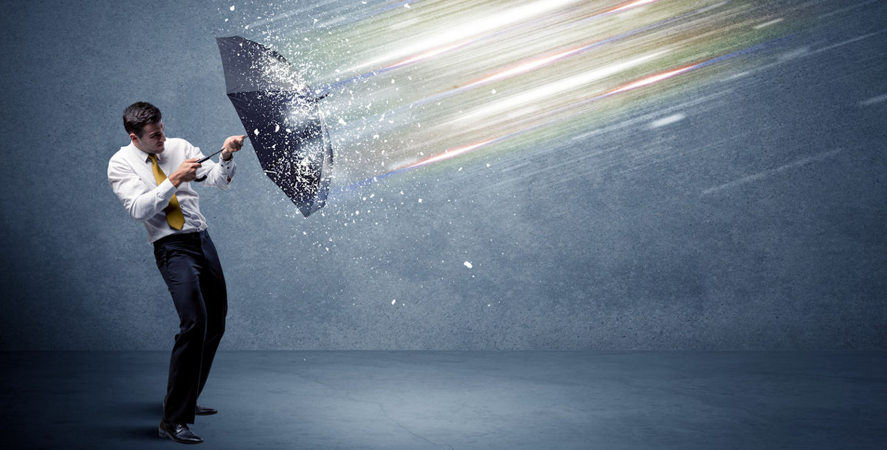 Geschäftsmann hält einen Regenschirm schützend vor sich