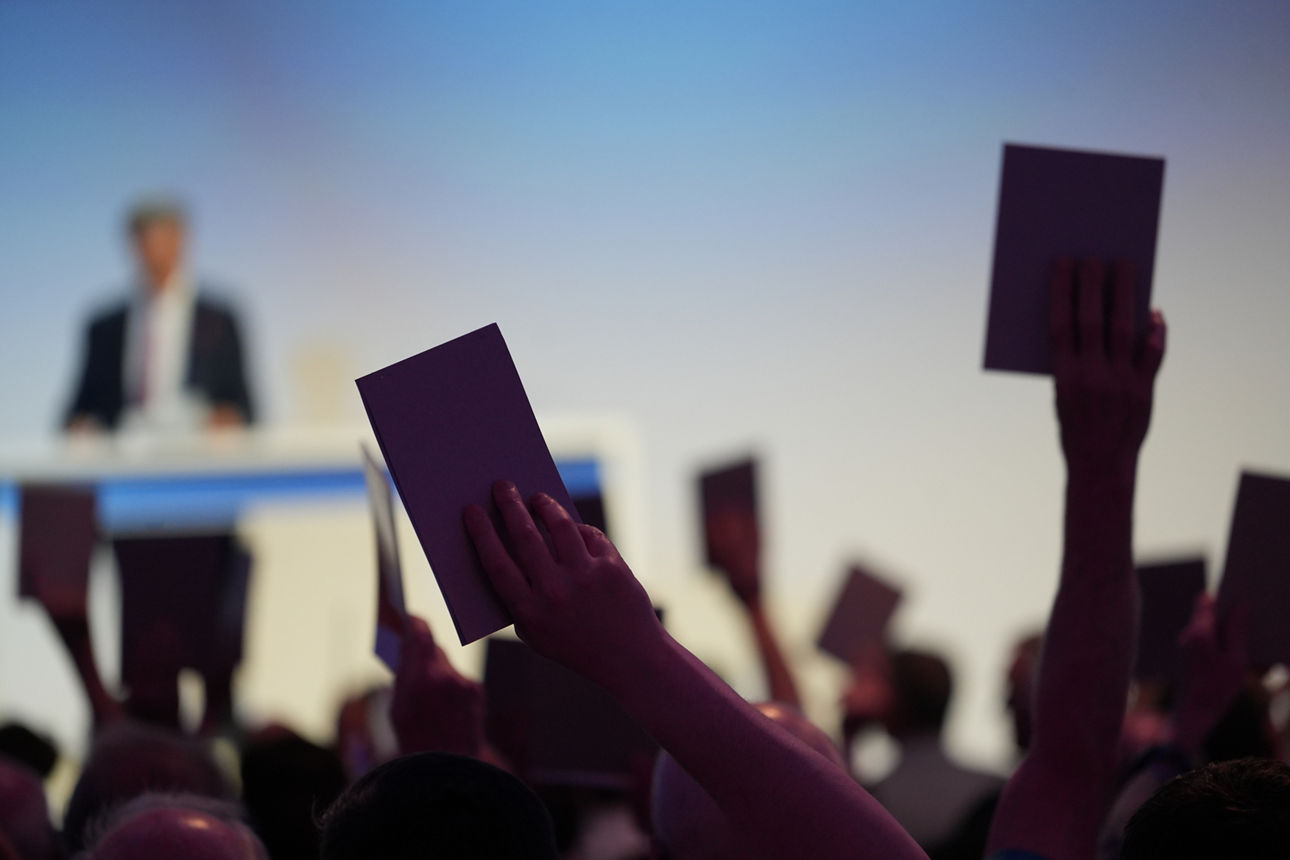 Abstimmung bei der Vertreterversammlung - Stimmkarten werden in die Höhe gestreckt