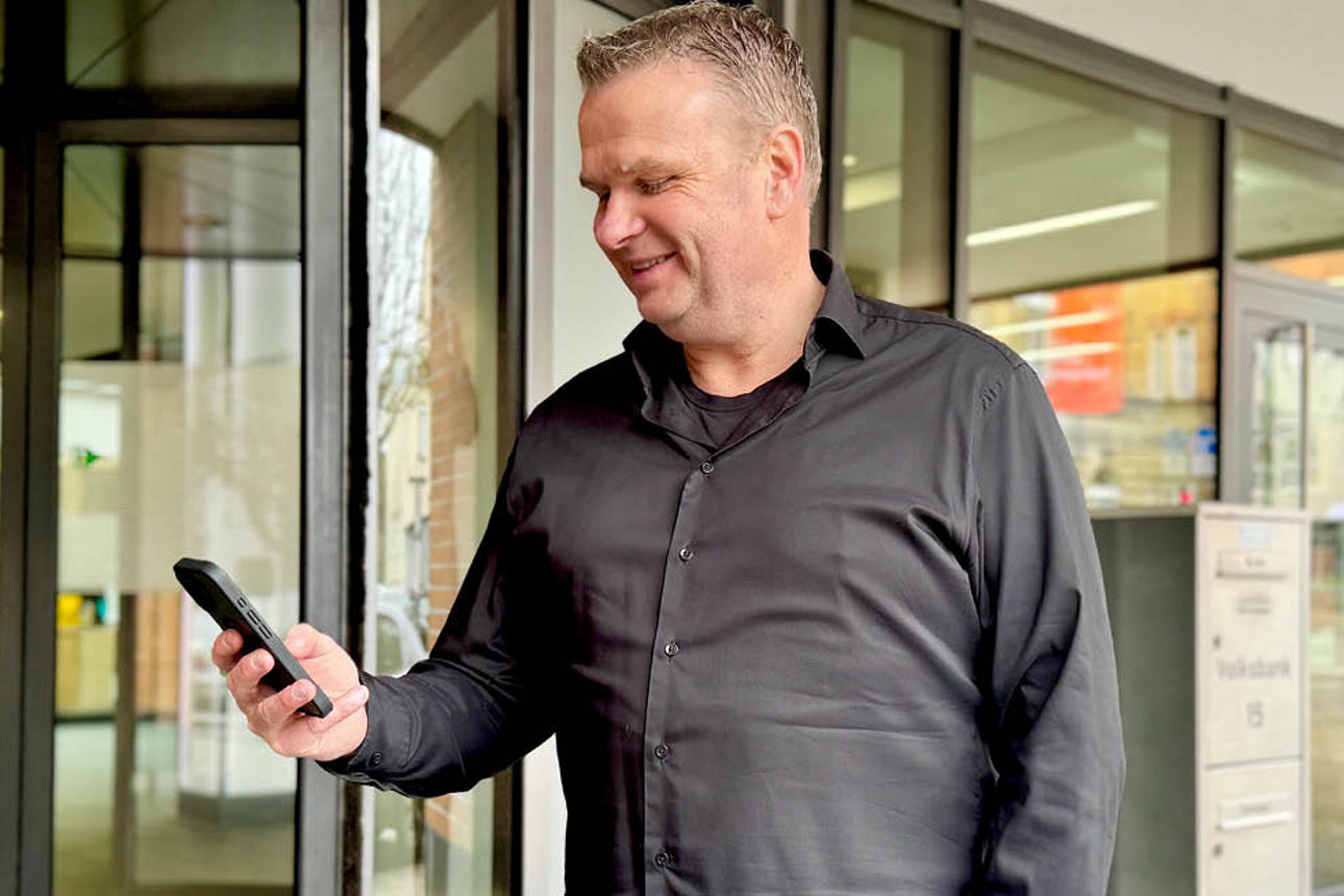 Sie sehen einen Mann mit einem Handy in der Hand.