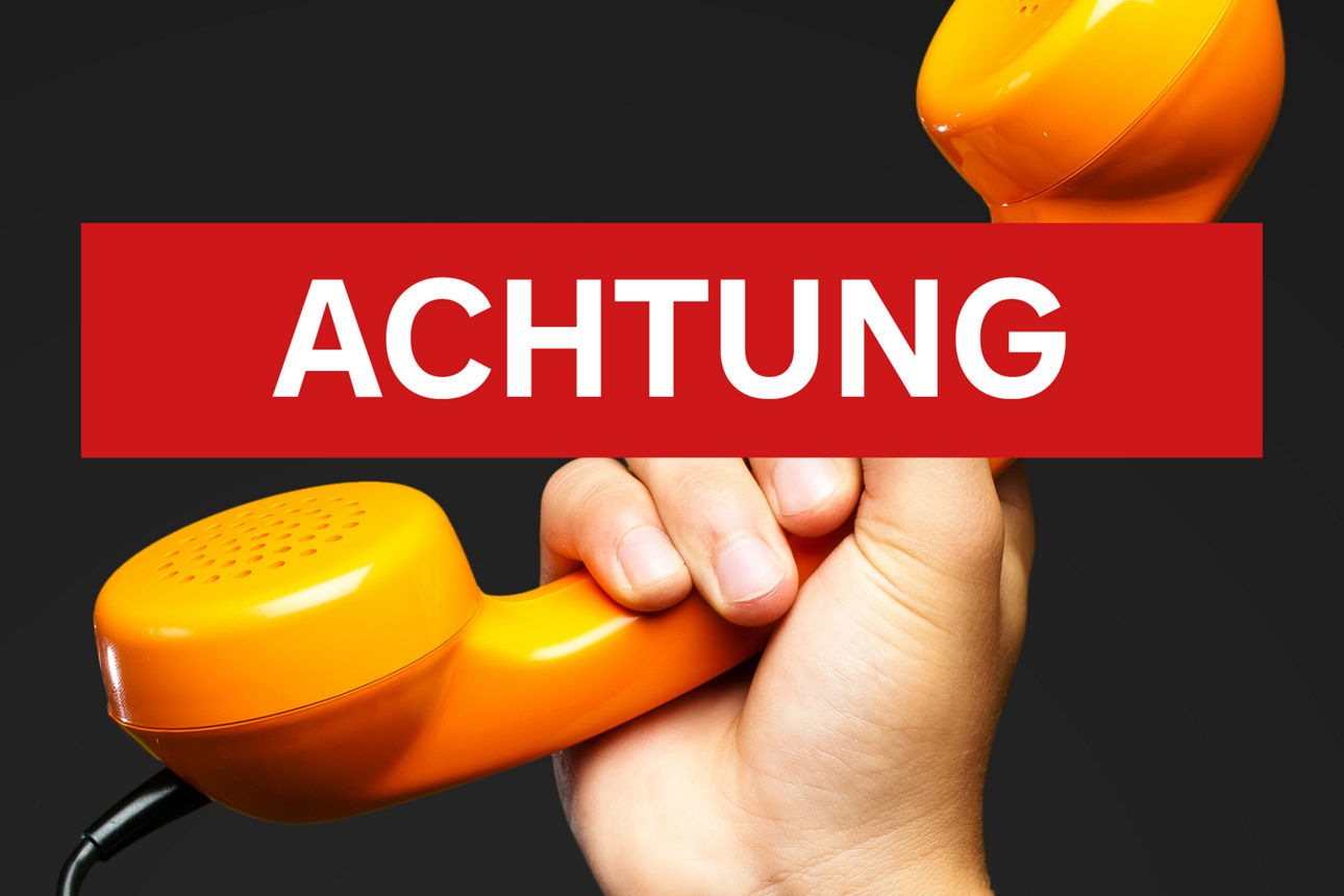 Ein orangner Telefonhörer mit roter Aufschrift "Achtung" - Hinweise zu Betrugsmaschen