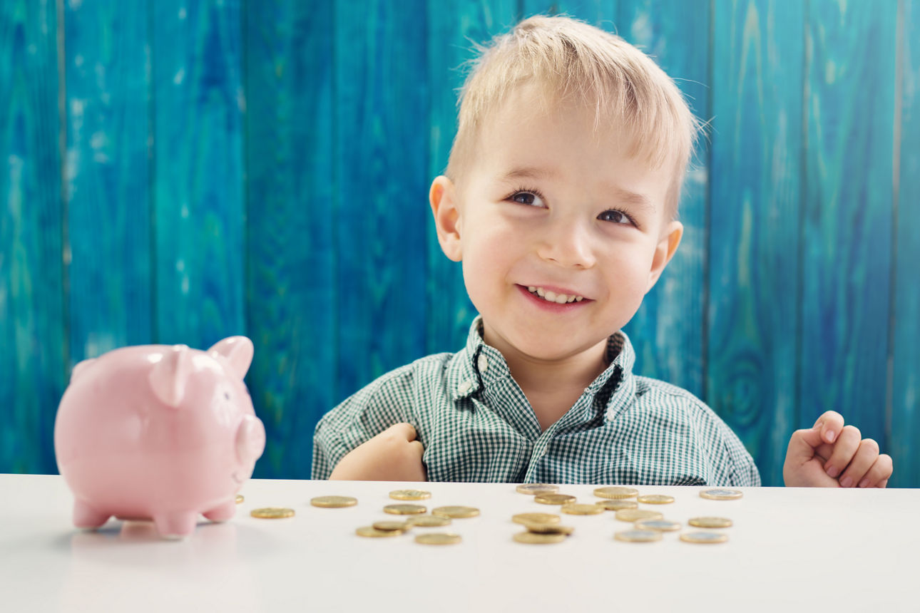 three years old child sitting st the table with money and piggybank. Happy boy with euro coins. Future childhood and education investment. Finance and savings concept