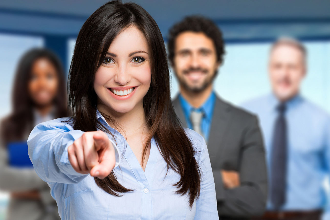 Eine Frau zeigt lächelnd in die Kamera.