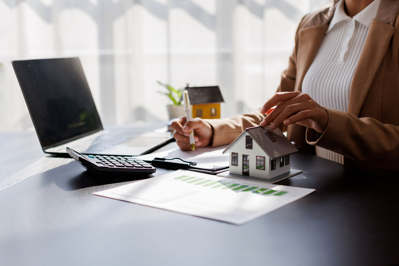 Eine Geschäftsfrau sitzt an ihrem Schreibtisch und arbeitet mit einem Taschenrechner