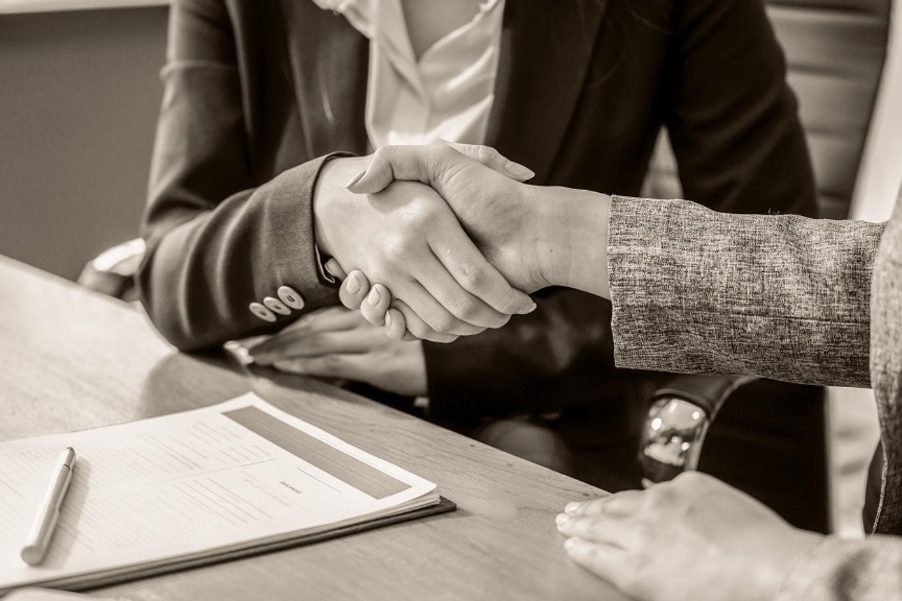 Zwei Menschen geben sich die Hand an einem Tisch