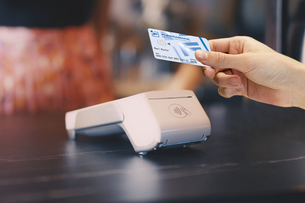 Person hält mit ausgestreckter Hand die girocard zum Kartenterminal hin