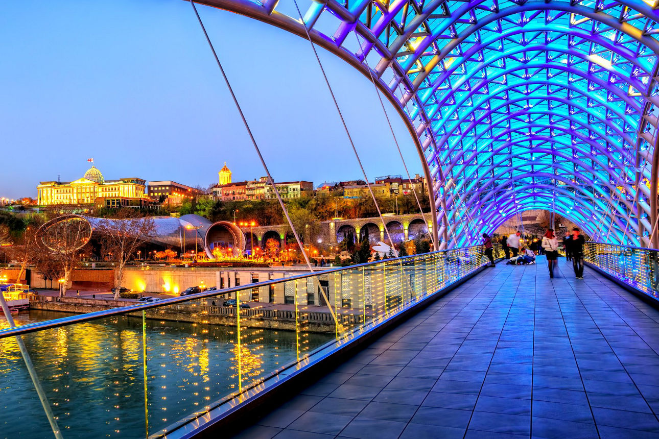 Blick von der blau beleuchteten Friedensbrücke zum Präsidentenpalast in Tiflis, Georgien