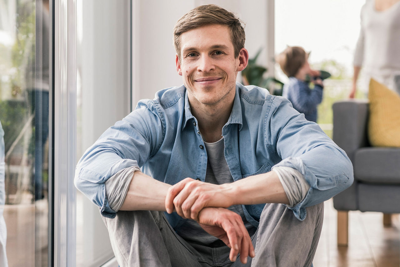 Mann sitzt auf dem Boden und grinst in die Kamera