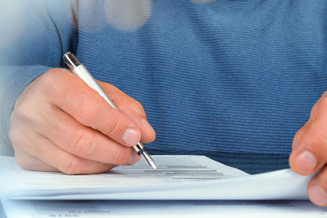 Hand mit Kugelschreiber und Formular
