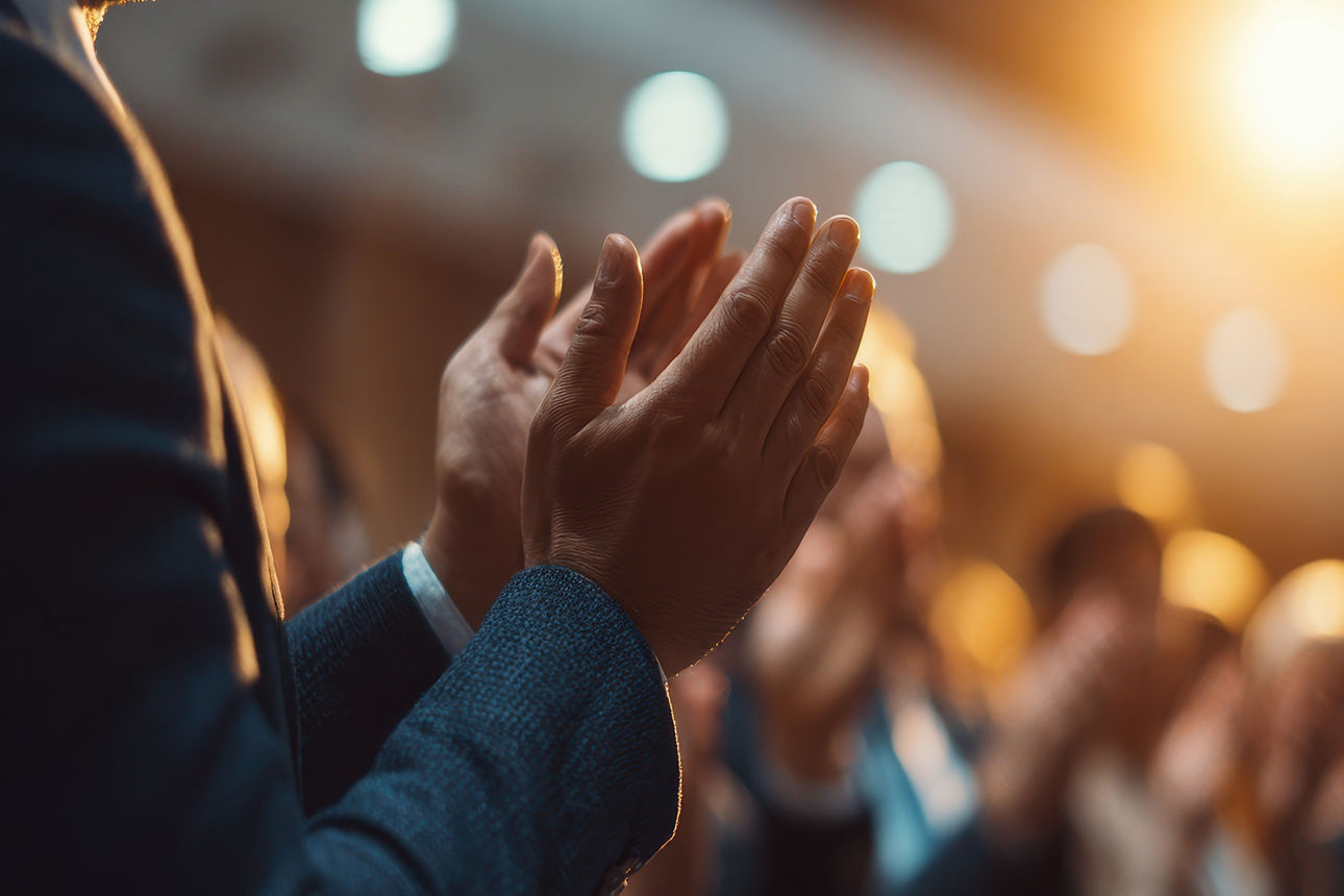 Applaus im Publikum bei Veranstaltung, Hände klatschen im warmen Bühnenlicht