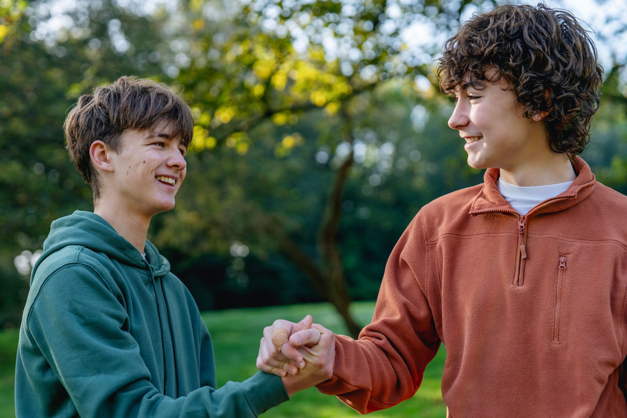 Zwei Jungs, die sich die Hand geben und in der Natur sind.