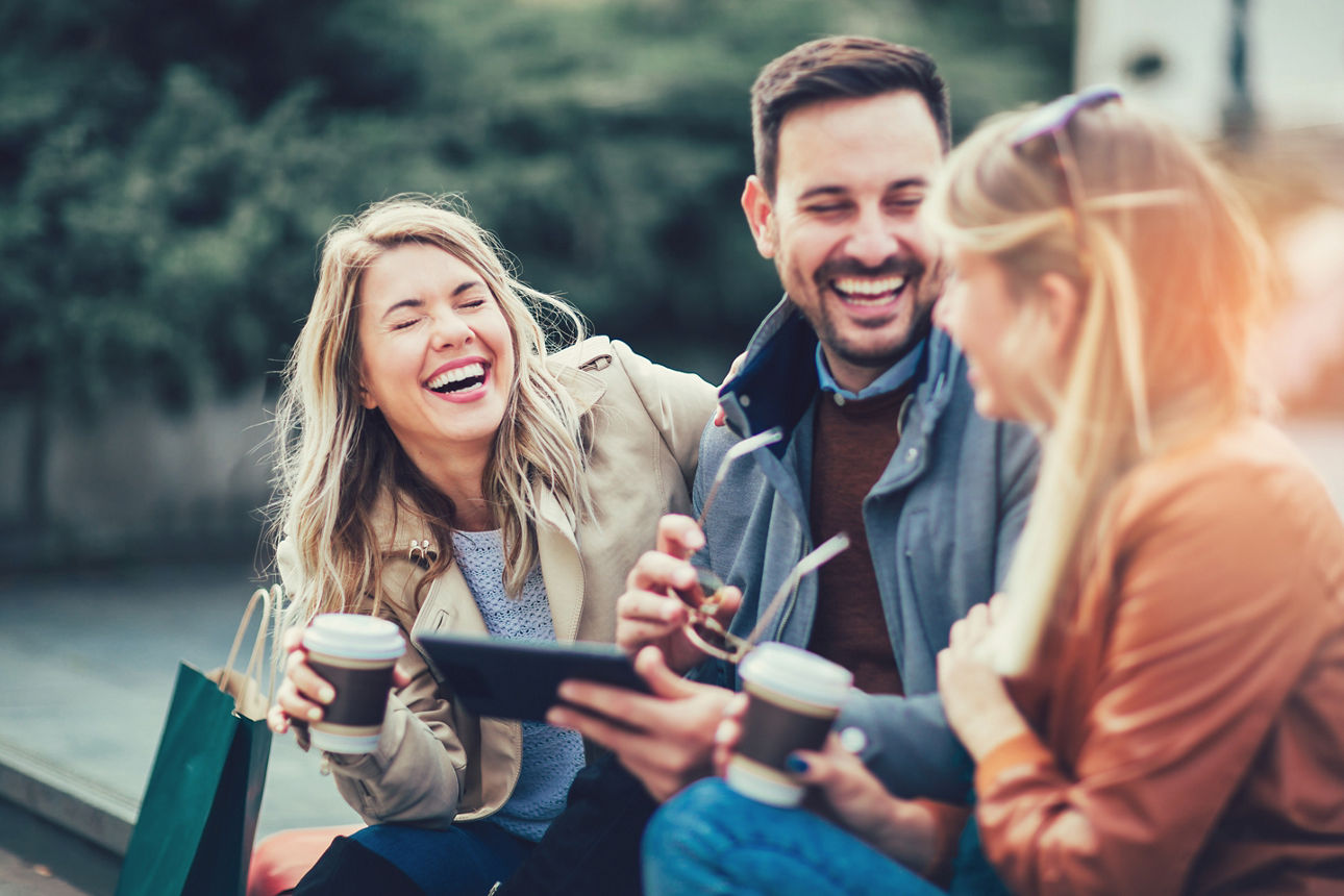 Gruppe von lächelnden Menschen trinken Kaffee in der Sonne