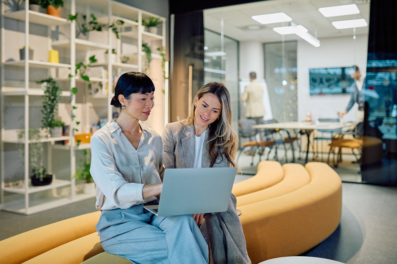 Geschäftsfrauen arbeiten während eines Büromeetings gemeinsam an einem Laptop
