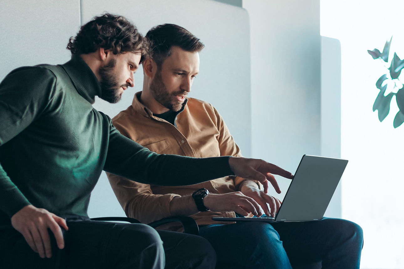 Zwei Männer schauen in einen Laptop und diskutieren miteinander - ErbNavigator
