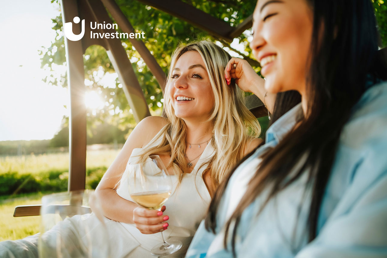 Glückliche Frauen, die auf der Verandaschaukel eines Weinguts ein Glas Weißwein in der Hand halten