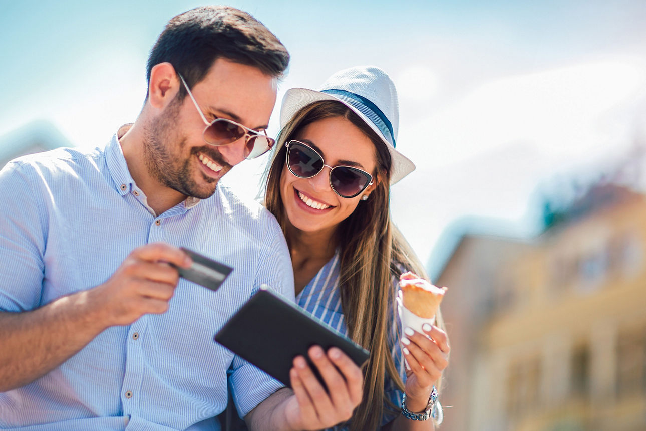 Ein lächelnder Mann mit Frau sehen auf ihr Handy und Ihre MasterCard