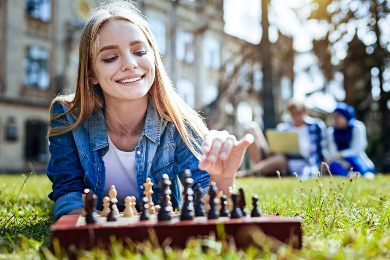 Junge Frau spielt auf einer Wiese Schach