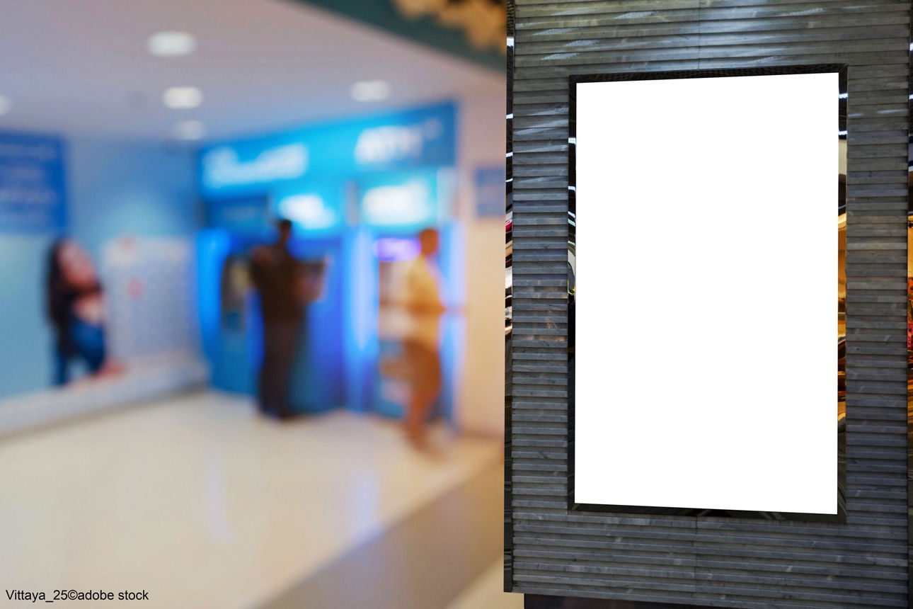 Digitaler Plakatrahmen in einem Raum mit Menschen im Hintergrund