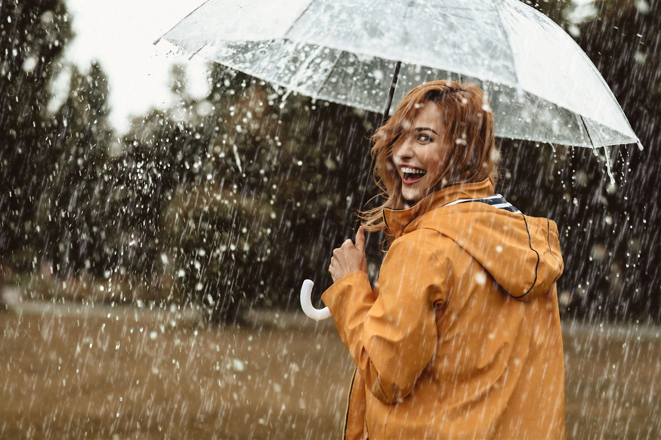 Lächelnde Frau mit Regenschirm im Regen