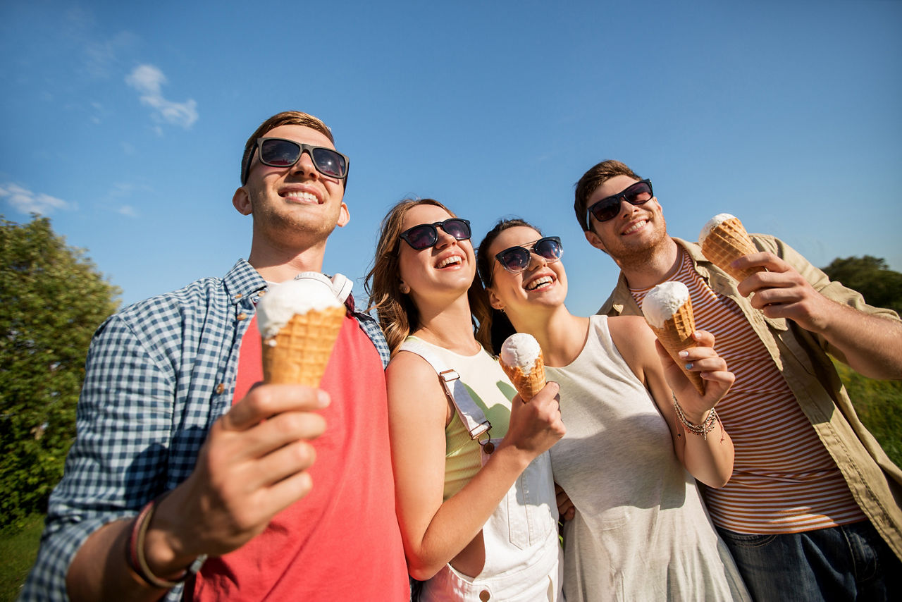 friendship, leisure and people concept - group of smiling friends with ice cream outdoors in summer