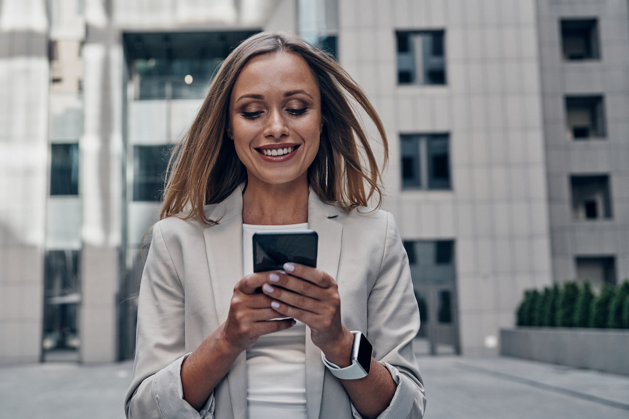 Frau hält lächelt ein Smartphone in Händen