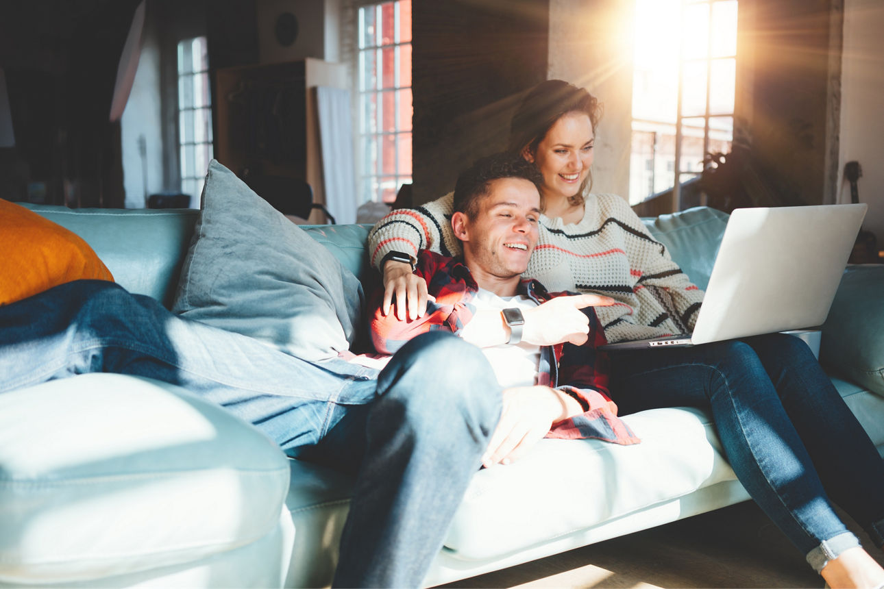 Paar liegt auf Couch vor Laptop 