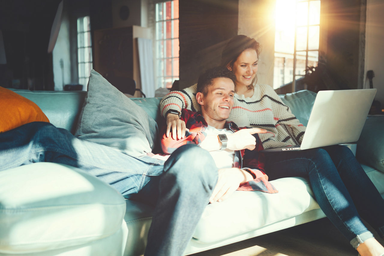 Paar sitzt auf der Couch und kümmert sich um Finanzen