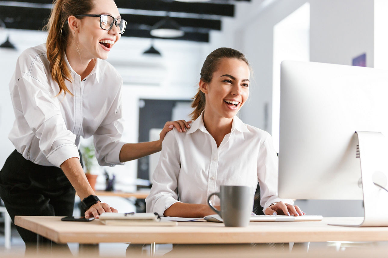 Zwei Geschäftsfrauen schauen glücklich in einen Computer
