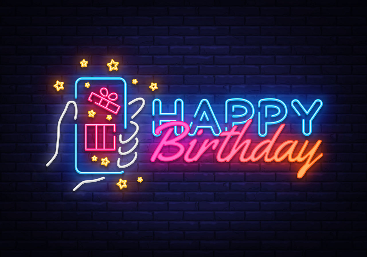 Happy Birthday Neon Leuchtschild mit Grafik eines Smartphones in der Hand , auf der ein Geschenk zu sehen ist.
