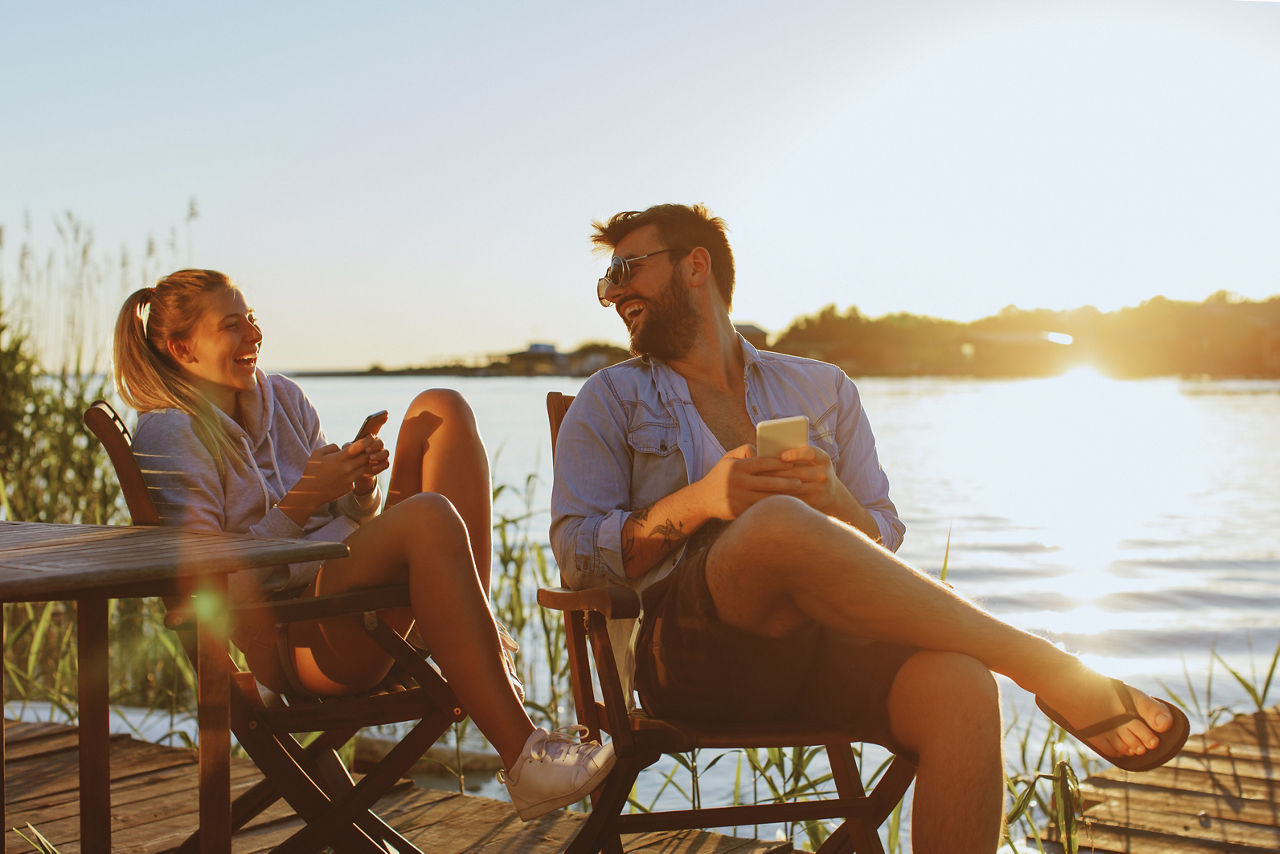 Junge Frau und Mann mit Smartphone am Fluss