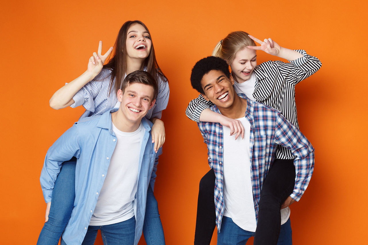 Zwei junge Männer tragen zwei junge Mädchen huckepack