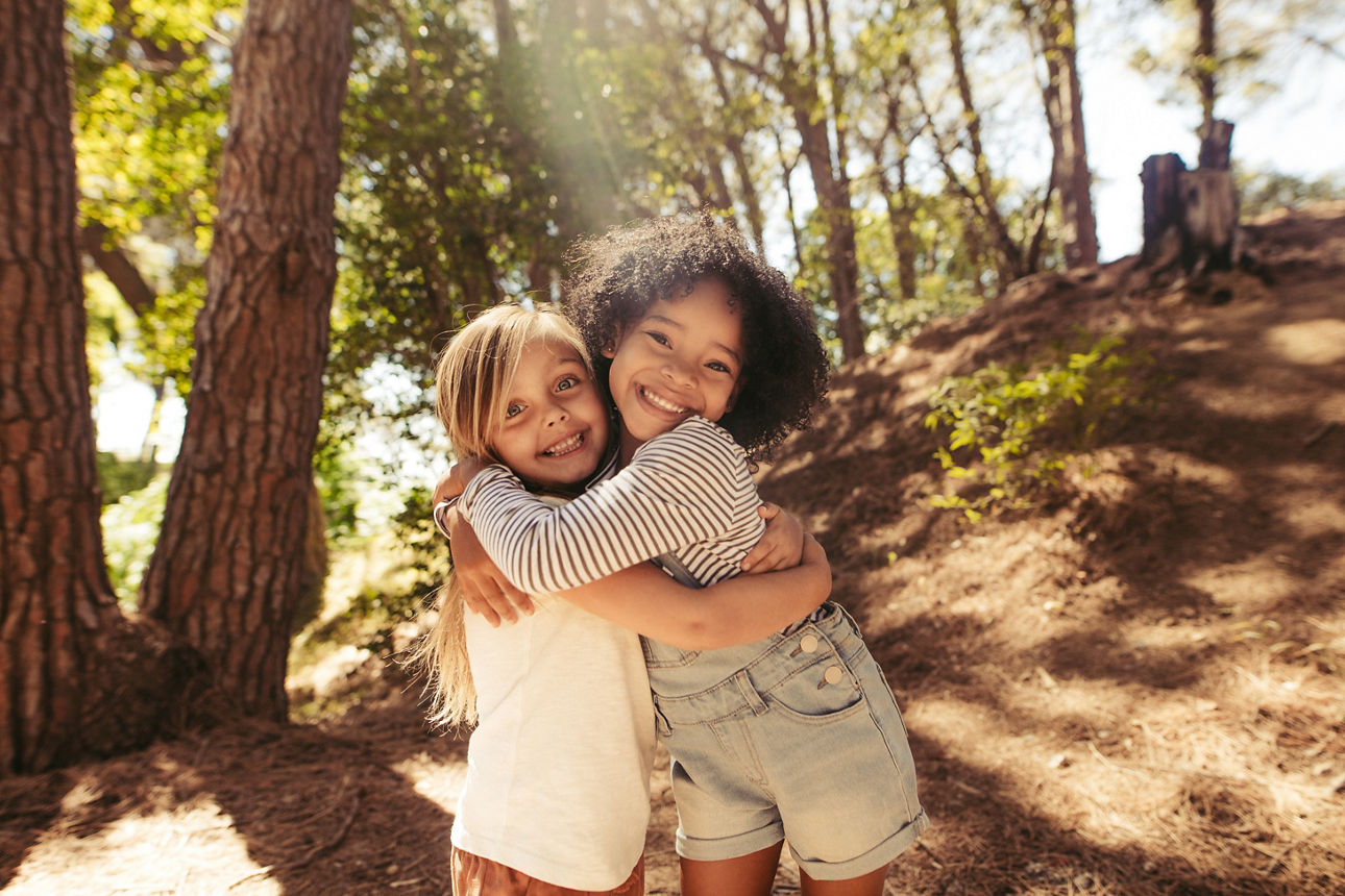 Zwei Mädchen umarmen sich im Freien. Kinder haben gemeinsam im Wald viel Spaß.