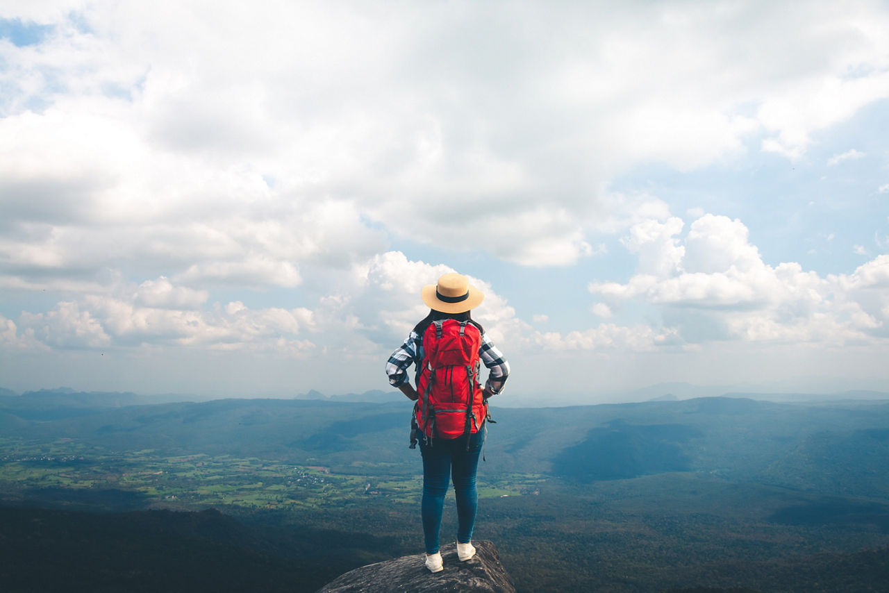 Rucksacktouristin schaut von einem Berg in die Ferne
