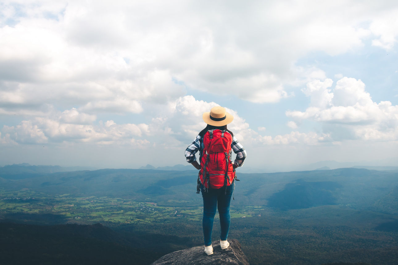 Rucksacktouristin schaut von einem Berg in die Ferne