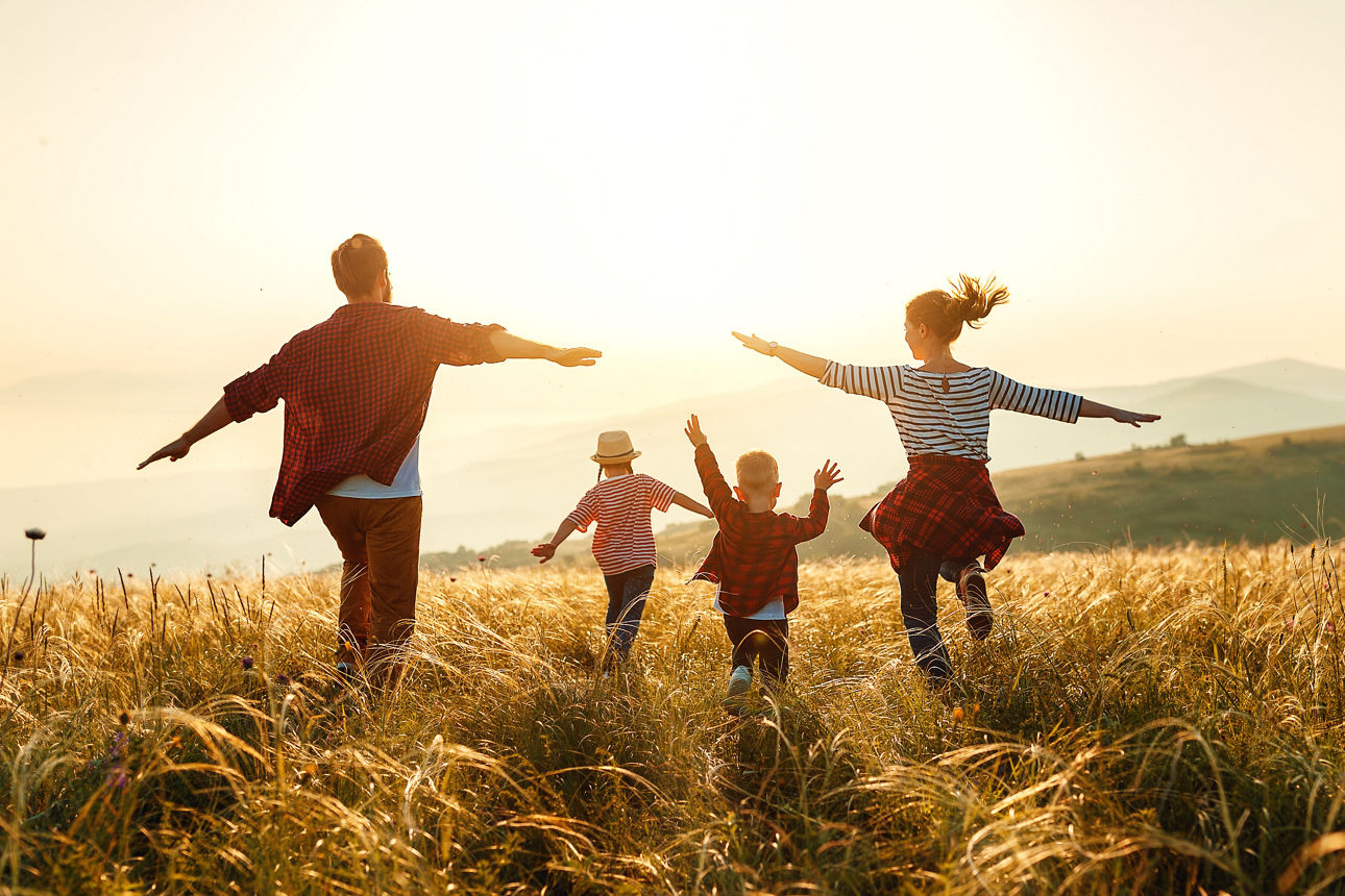 Familie läuft über Feld in Richtung Sonne