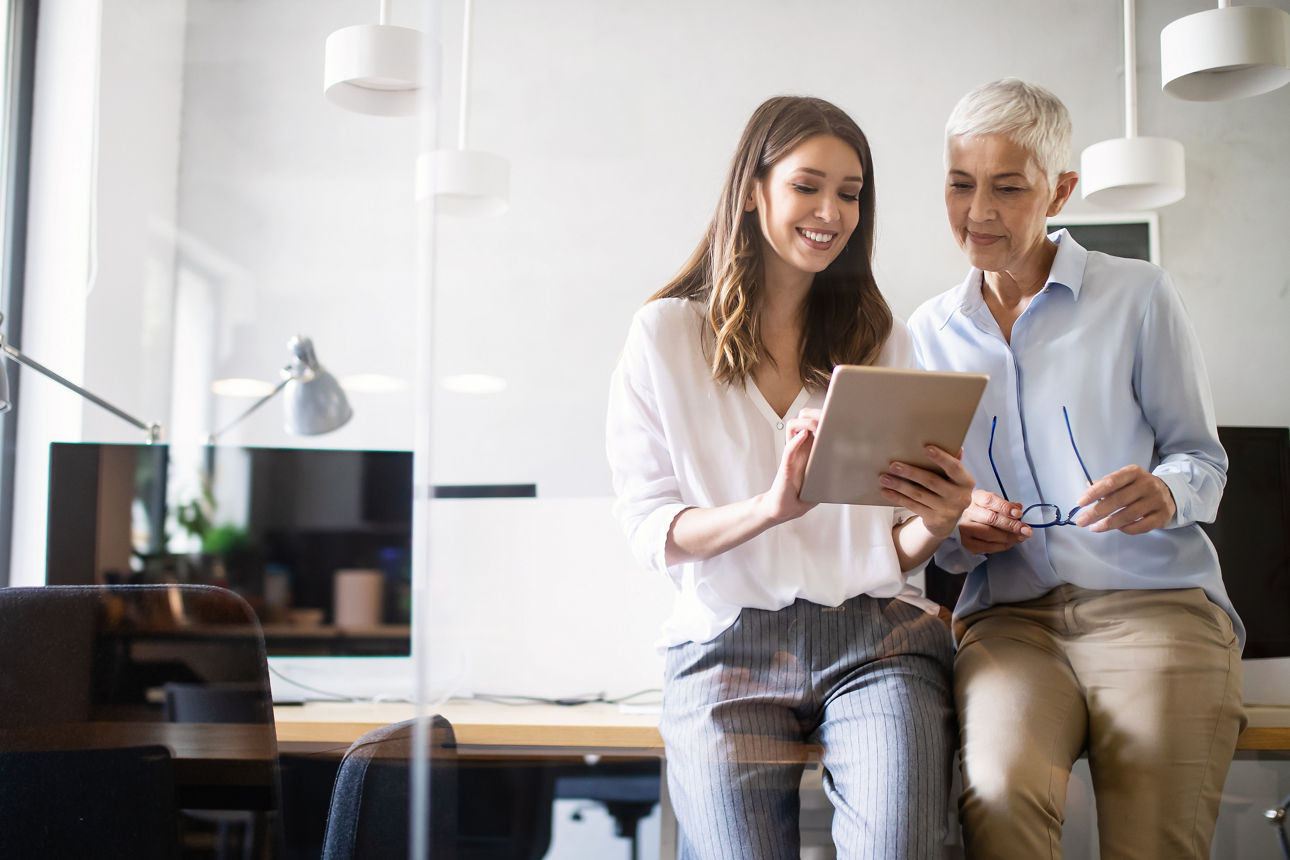 Zwei Frauen sitzen zusammen im Büro und unterhalten sich
