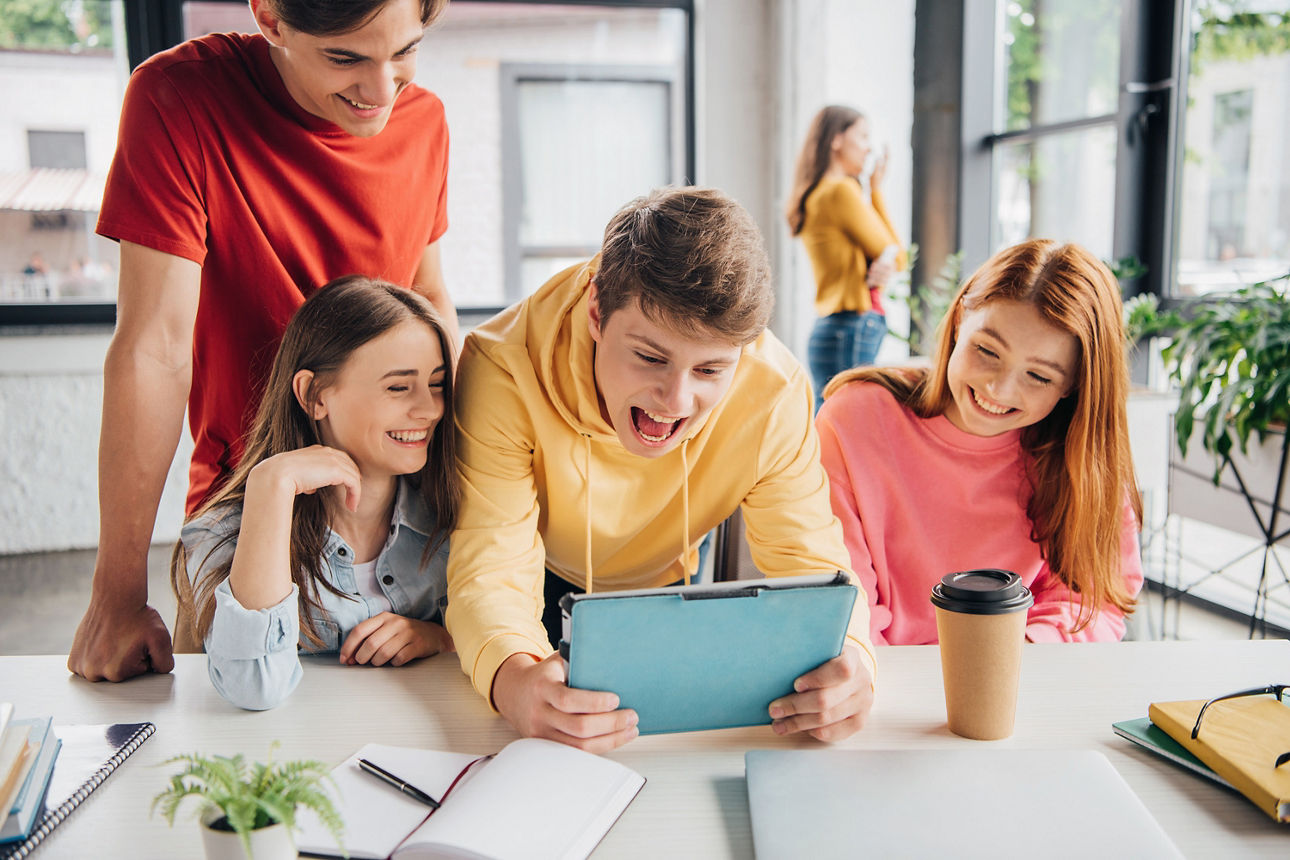 group of smiling schoolchildren using digital tablet in classroom