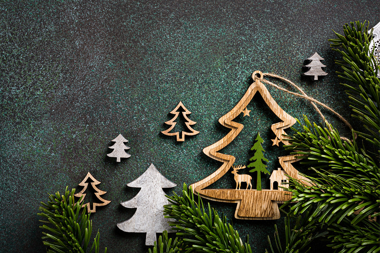 Tannenzweige und Tannenbaumschmuck aus Holz vor einem grünen Hintergrund