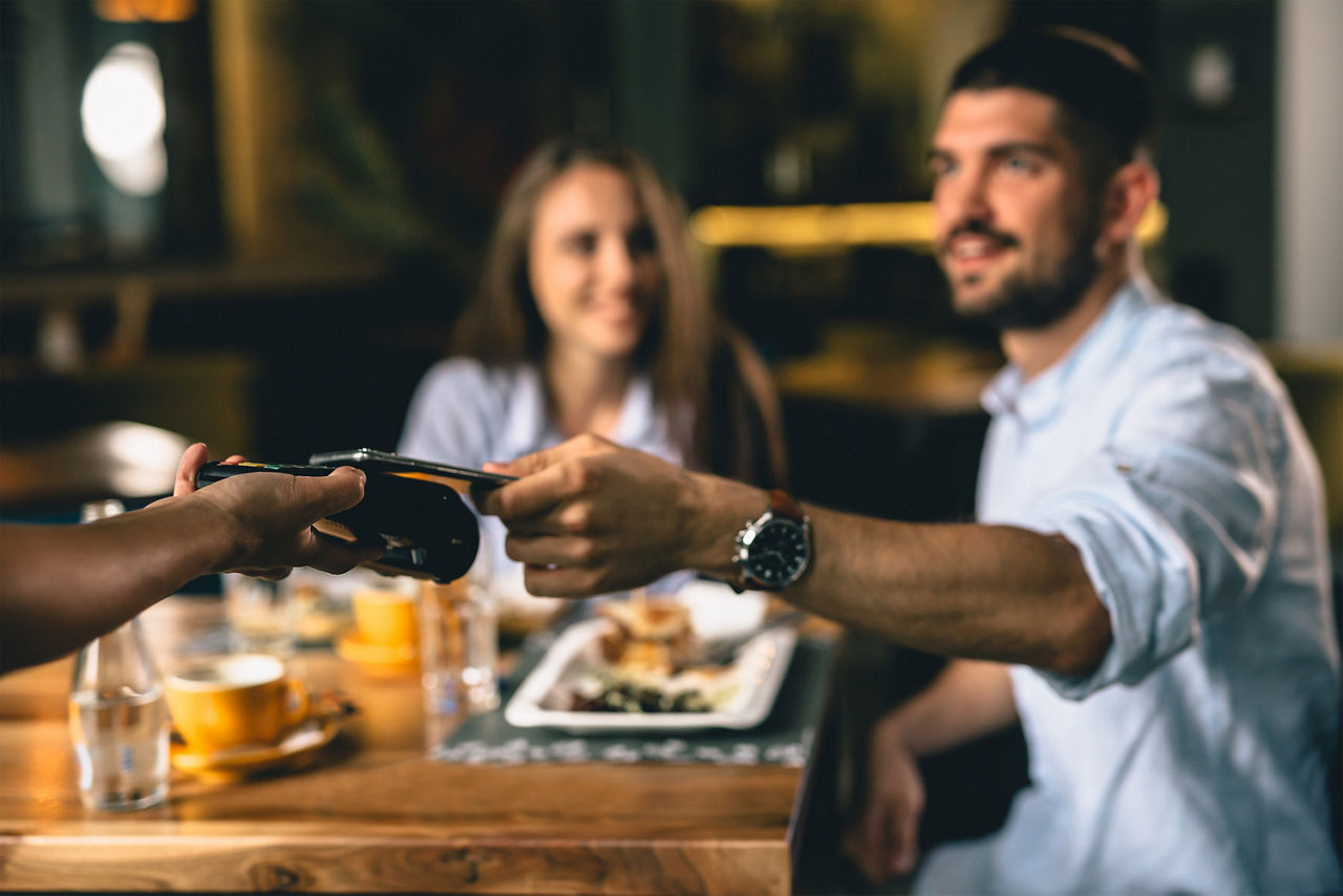 Ein Mann zahlt sein Essen mit seiner MasterCard auf einem Kartenlesegerät