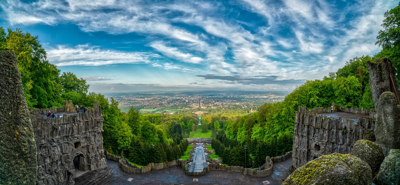 Blick auf Kassel durch Bäume und ein antikes Gebäude.